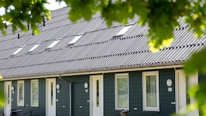 A row of motel rooms with individual doors, a small table with chairs, and a window with a basket on the windowsill. - Cozy Forest-edge Home (Rheezerveen)