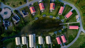 An aerial view of a residential area with houses, a small pond, and a curved road. - Large Countryside Group Stay (Bant)