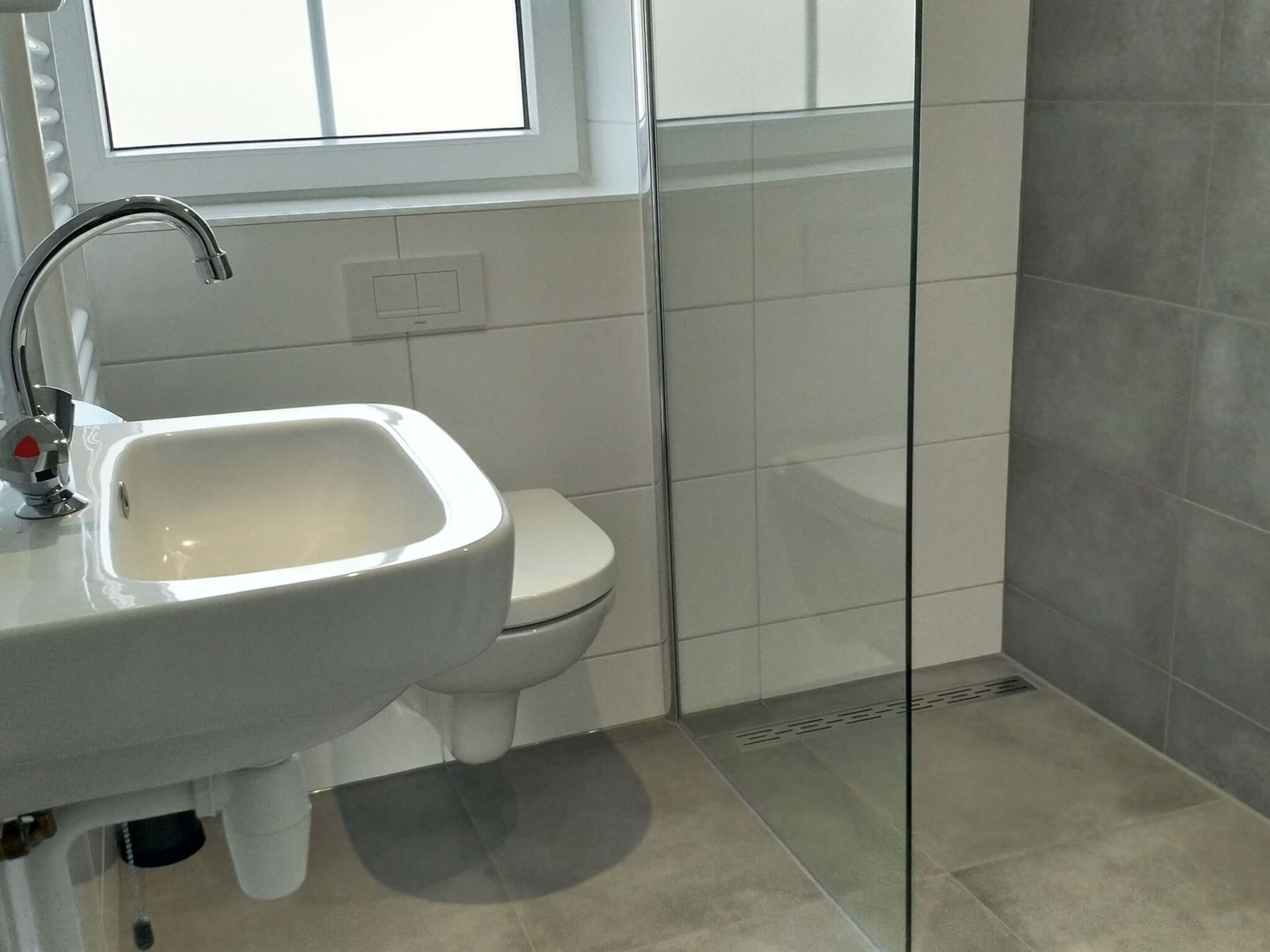 A bathroom with a white sink, a toilet, and a window.