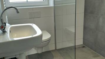 A bathroom with a white sink, a toilet, and a window.