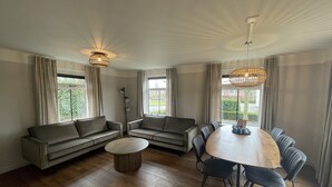 A modern living room with a sofa set, a round dining table, and a floor lamp. - Large Countryside Group Stay (Bant)