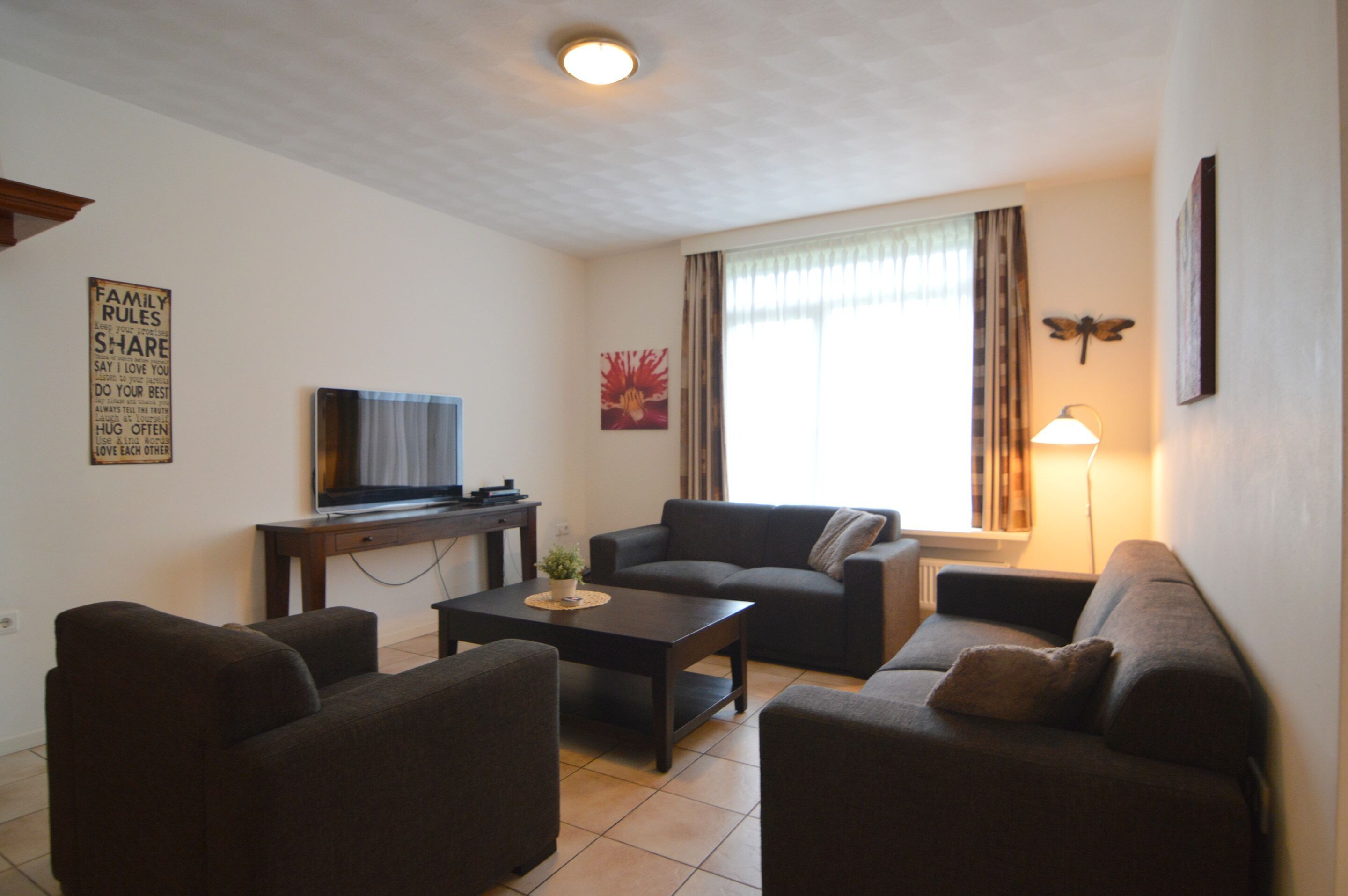 Ein Wohnzimmer mit Fernseher, Sofas, Couchtisch und Lampe.