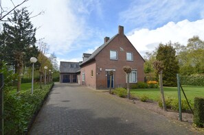 A brick house with a sloped roof, a front door, and a small garden area with a pathway leading to the entrance.