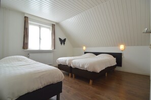 A room with two beds, a window with curtains, a wall-mounted butterfly decoration, and a sloped ceiling.