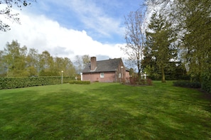 A house with a brick exterior, a well-maintained lawn, and a hedge in the foreground.