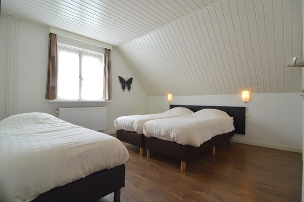 A room with two beds, a window with curtains, a wall-mounted butterfly decoration, and a sloped ceiling. - Lovely Group Home With Lots of Privacy, Ideal for Families and Friends (Valkenswaard)