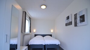 A modern bedroom with a double bed, a bedside table, a mirror, and two wall-mounted light fixtures.