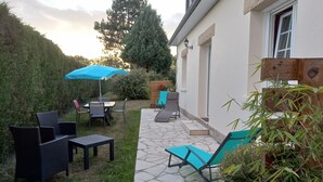 An outdoor patio with stone flooring, a table, chairs, a blue umbrella, and a lounge chair. - Charming Breton House in Henansal (Henansal)