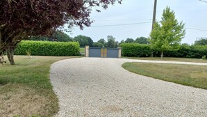 A gravel driveway leading to a building with a gated entrance, surrounded by greenery and a tree. - Charming Breton House in Henansal (Henansal)