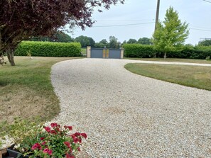 A gravel driveway leading to a building with a gated entrance, surrounded by greenery and a tree. - Charming Breton House in Henansal (Henansal)