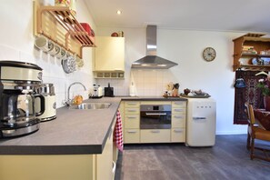 Una cocina con cafetera, tostadora, lavabo, estufa y refrigerador.