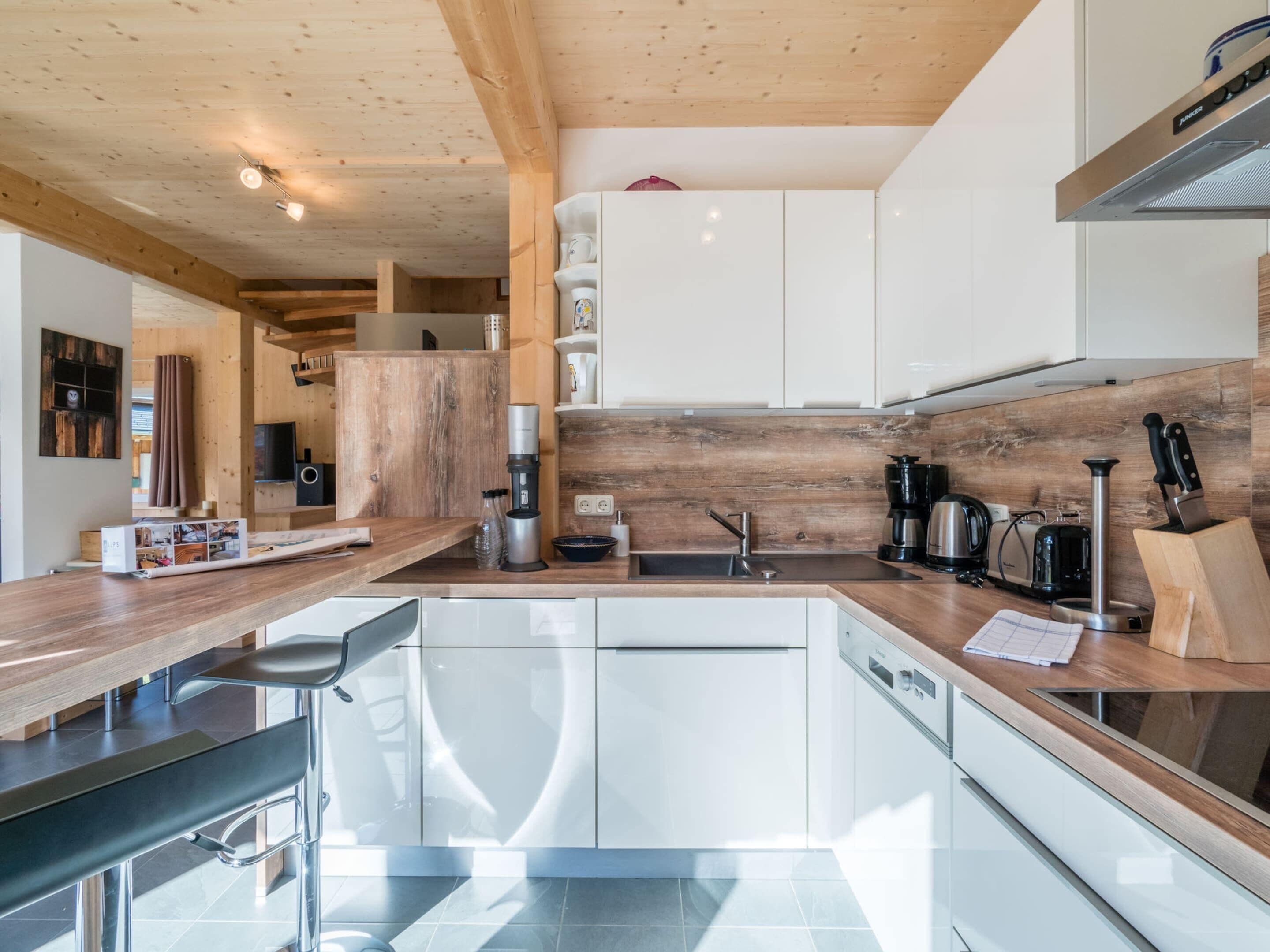 Une cuisine moderne avec des poutres en bois, des armoires blanches et un pare-feu en bois.