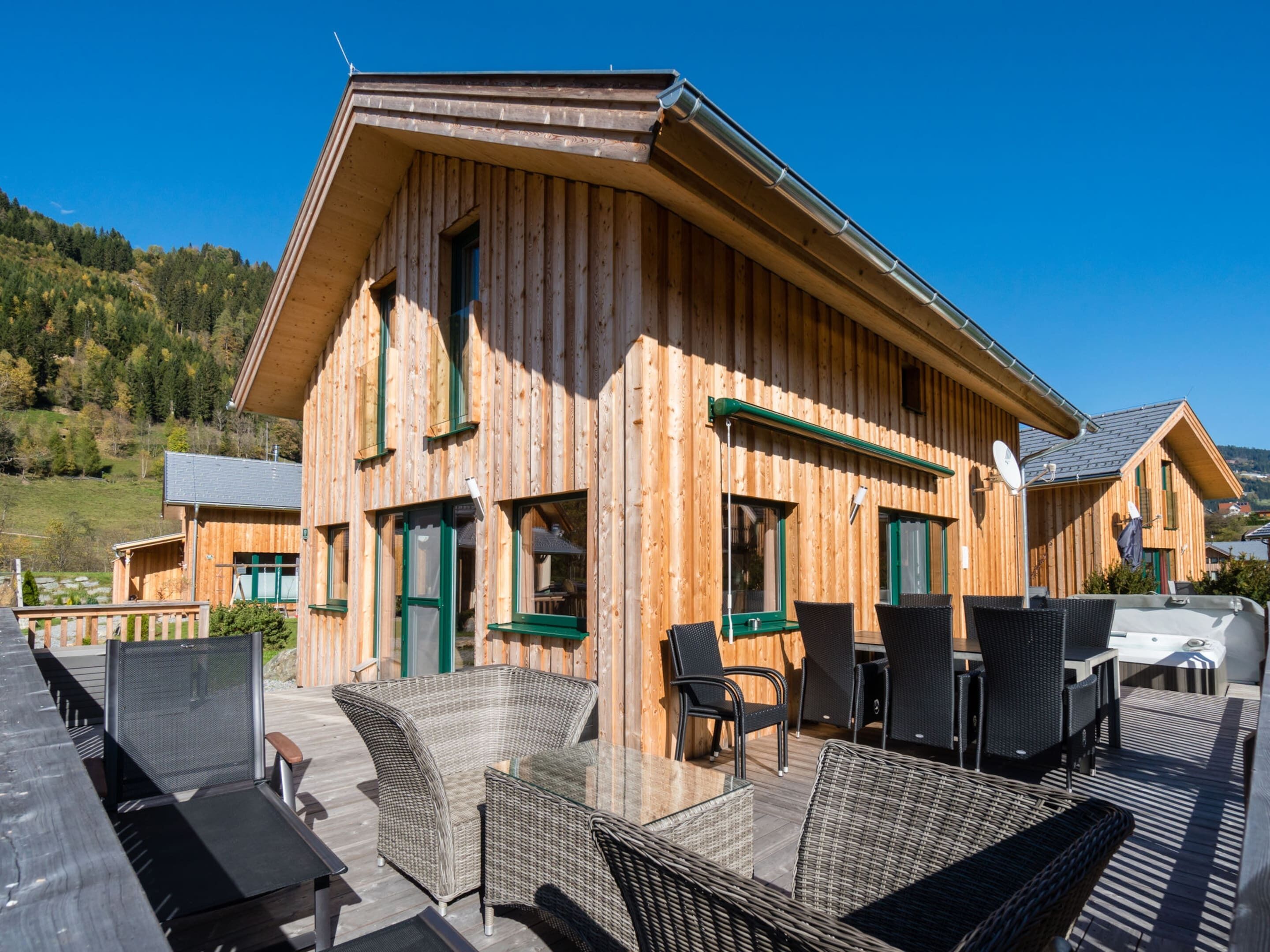 Een houten chalet met buitenmeubilair en uitzicht op het omliggende landschap.