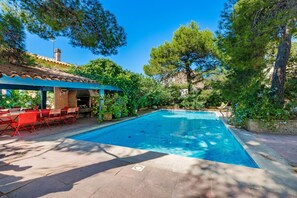 A swimming pool with a covered patio area, outdoor seating, and surrounding greenery. - Villa in Martigues Near Mediterranean Beach (Martigues)