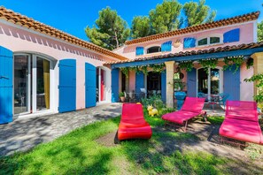 A villa with a patio, blue shutters, and red lounge chairs. - Villa in Martigues Near Mediterranean Beach (Martigues)