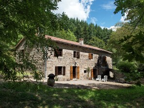 A stone house with a tiled roof, surrounded by trees and a gravel driveway. - Secluded Stone Villa Retreat (Saint-Pierre-sur-Doux)