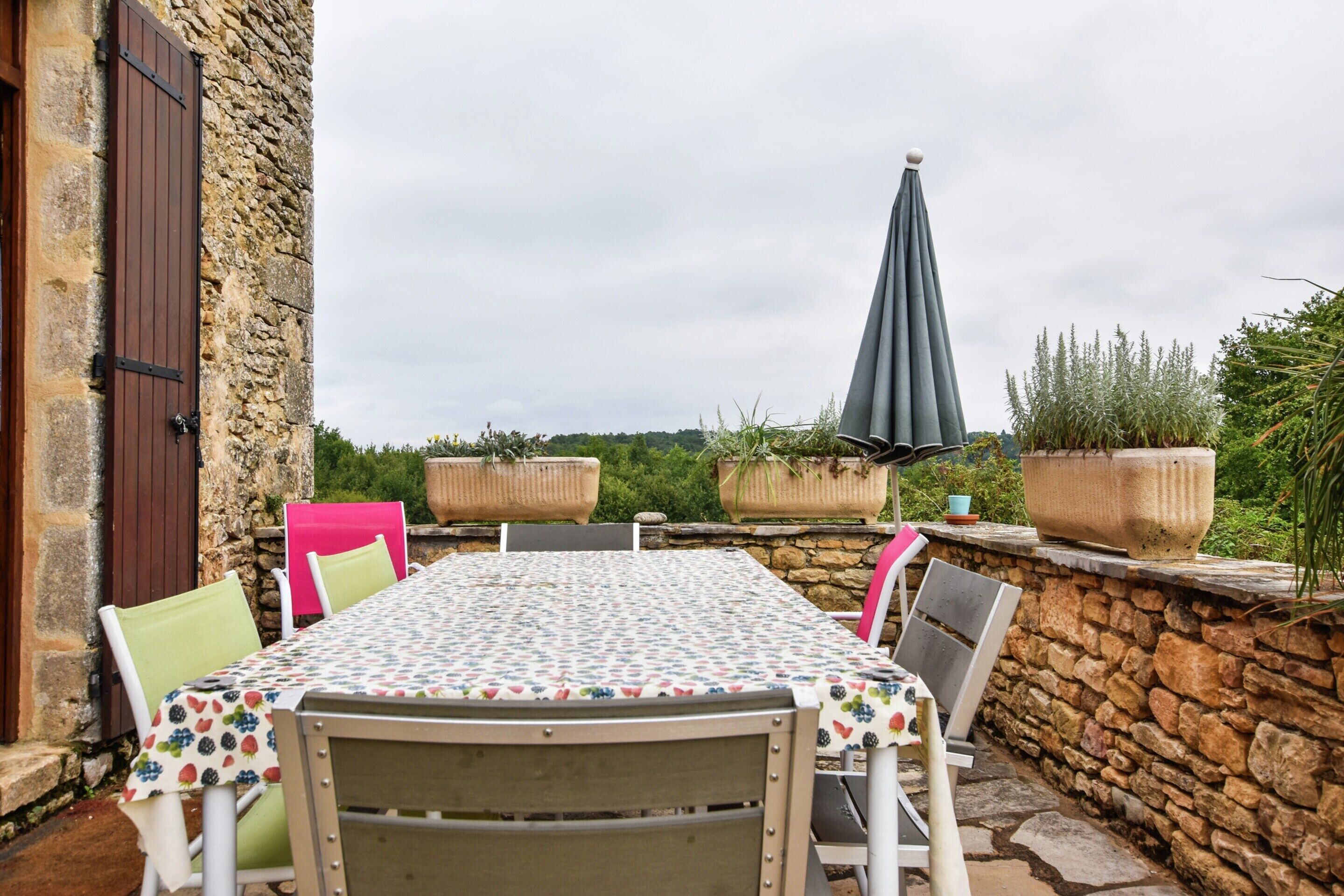 An outdoor dining area with a table, chairs, and potted plants.