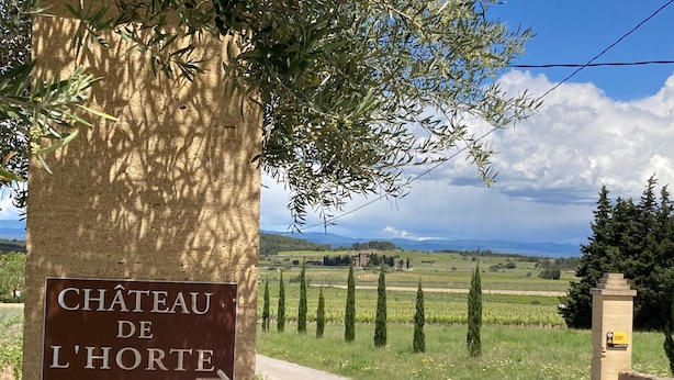 Un cartel del Château de l'Horté con un sendero que lleva a un paisaje rural.