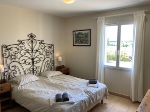 A bedroom with a bed, two bedside tables, a nightstand, a window with curtains, and a framed picture on the wall. - Cosy Villa With Pool (Montbrun-des-Corbières)