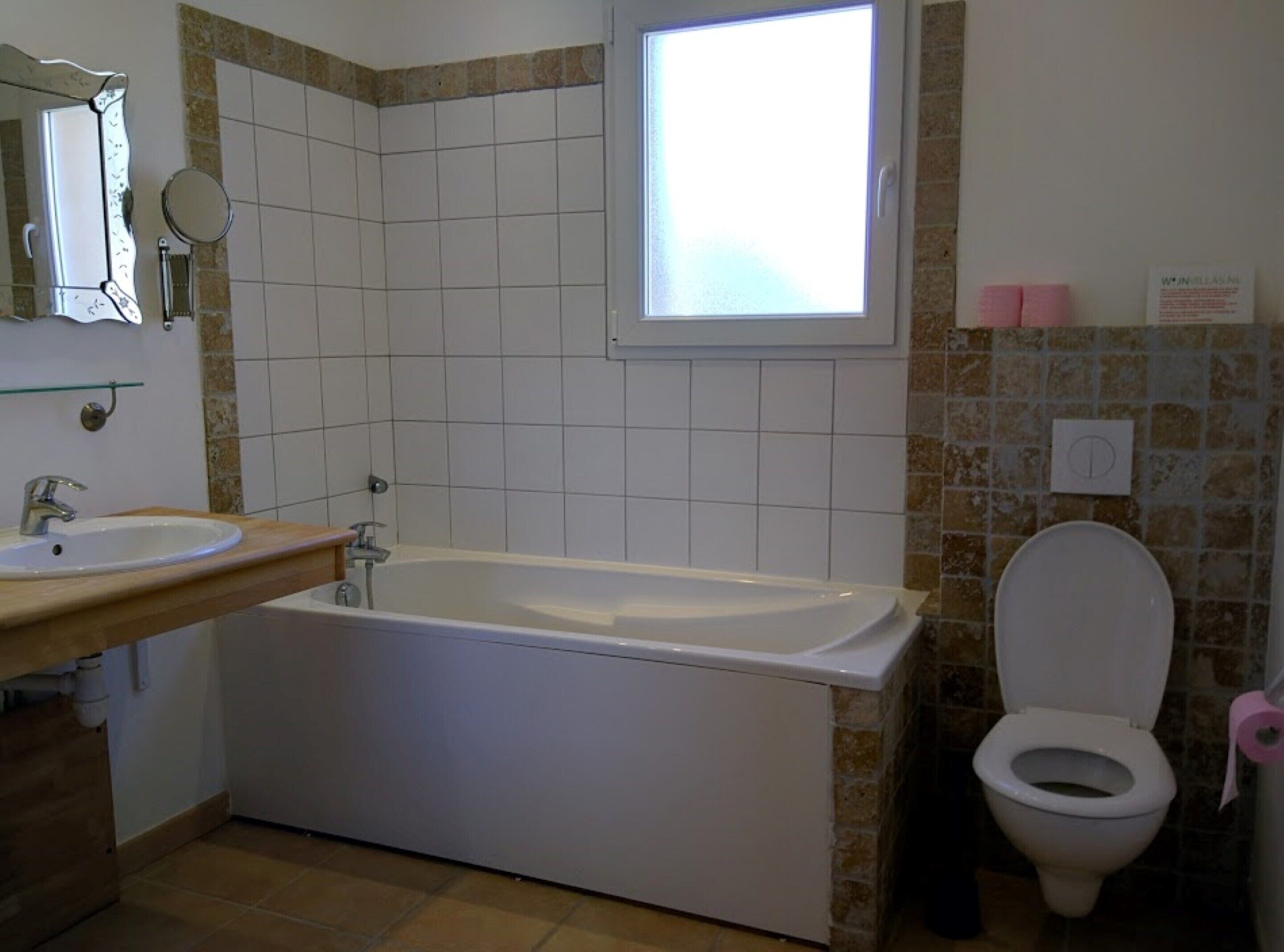 Un baño con bañera, lavabo, inodoro y ventana.