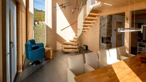 Een modern interieur met een houten trap, een eethoek en een open haard.
