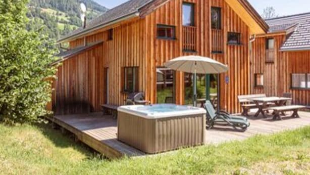 A wooden cabin with a hot tub, outdoor seating, and a deck. - Charming Chalet With Whirlpool (Sankt Georgen am Kreischberg)
