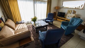 Ein Wohnzimmer mit einer Couch, zwei Sesseln, einem Couchtisch und einem Fernseher.