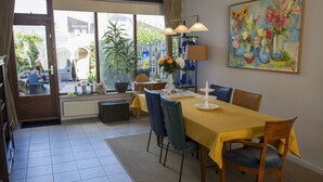 Ein Essbereich mit Tisch für vier Personen, Stühlen, einer Lampe und einem Bild an der Wand.