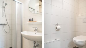 Ett badrum med en duschkabin med glasväggar, ett handfat med en spegel ovanför och en toalett.