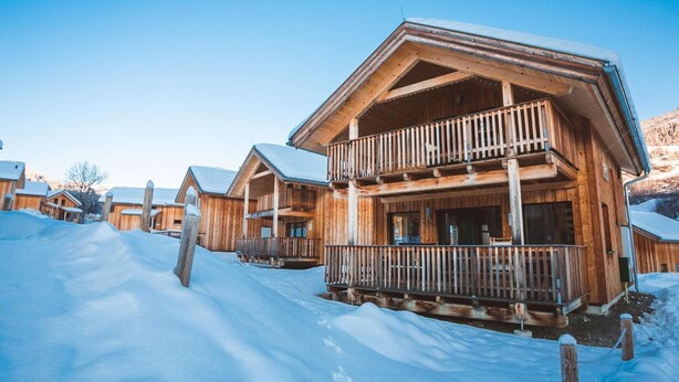 Un chalet en bois doté d’un balcon, entouré de neige.