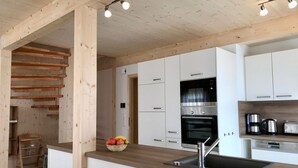 Une cuisine moderne avec des armoires blanches, des appareils en acier inoxydable et un plafond en bois.