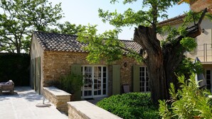 Un bâtiment en pierre avec un toit en tuiles, de grandes fenêtres et un arbre au premier plan.