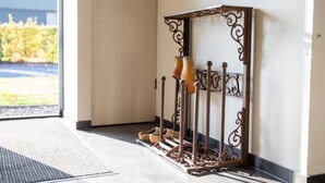 A metal shoe rack with a decorative design against a wall, located in a hallway with a view of a building outside. - Classy Holiday Home in Alphen With Garden (Alphen)