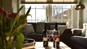 A cozy living room with a wooden coffee table, a vase of tulips, and two wine glasses. - Villa in Schoorldam With Garden (Warmenhuizen)