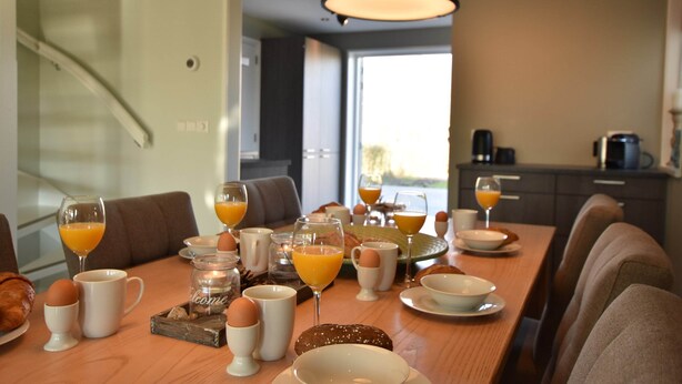 A breakfast table set with eggs, toast, and orange juice in a modern kitchen with a view. - Villa in Schoorldam With Garden (Warmenhuizen)