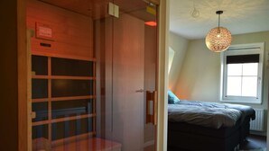 A bedroom with a bed, a window, and a hanging light fixture. - Villa in Schoorldam With Garden (Warmenhuizen)