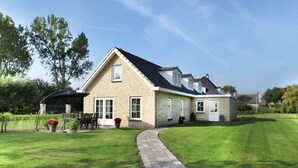 A two-story house with a paved driveway leading to a covered patio area. - Villa in Schoorldam With Garden (Warmenhuizen)