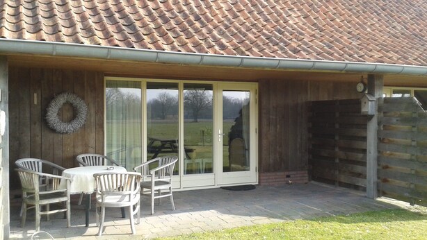 A patio area with a table and chairs, a covered seating area with a bench, and a wooden fence.