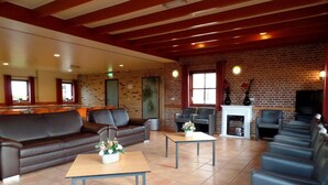 Un salón amplio con pared de ladrillo, sofás de cuero y chimenea.