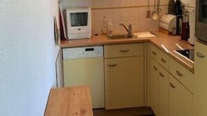 A small kitchen with a microwave, sink, and wooden table. - Chalet in Vallandry Near Paradiski Ski Area (Landry)