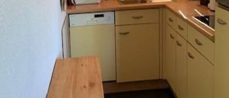 A small kitchen with a microwave, sink, and wooden table.