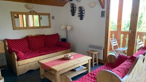 A cozy room with a wooden sofa, a small table, and a bench. - Chalet in Vallandry Near Paradiski Ski Area (Landry)