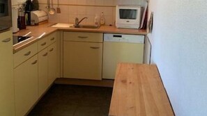 A compact kitchen with a microwave, sink, and a wooden table. - Chalet in Vallandry Near Paradiski Ski Area (Landry)
