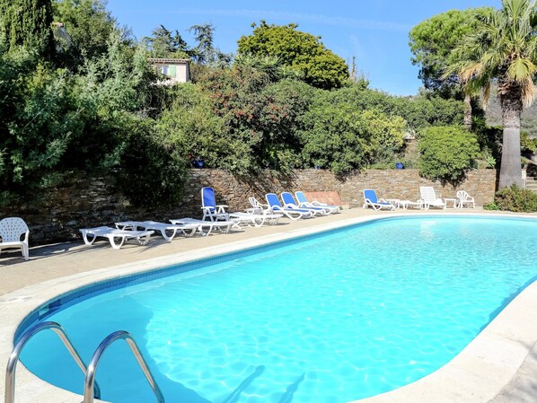 A swimming pool with lounge chairs and a stone wall. - Holiday Home in Bormes-les-mimosas With Pool (Bormes-Les-Mimosas)