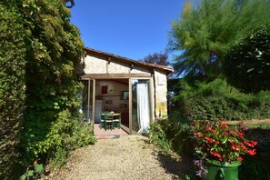 A house with a patio, a dining area, and a kitchen visible through an open door. - Peaceful Villa in Saint-jory (Saint-Jory-las-Bloux)