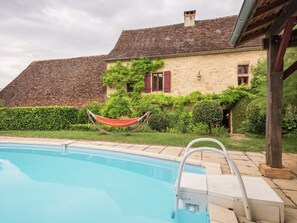 A swimming pool with a wooden deck, a hammock, and a stone house with red shutters. - Peaceful Villa in Saint-jory (Saint-Jory-las-Bloux)