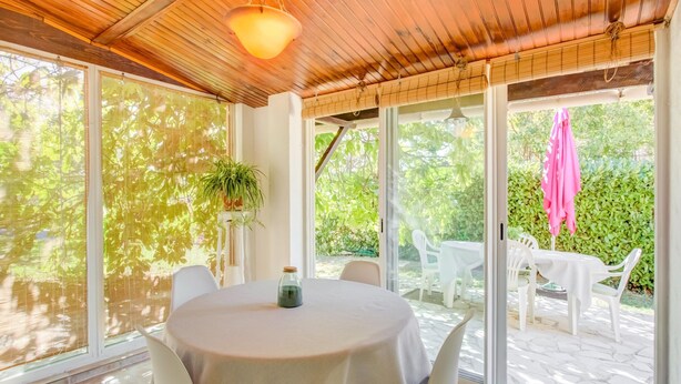 A sunlit room with a round table, chairs, a hanging light fixture, and large windows. - Peaceful Garden Retreat, Berre (Berre-des-Alpes)