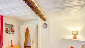 A room with a wooden bench, a sofa with a red pillow, a lamp, a painting, and a door leading to another room. - Peaceful Garden Retreat, Berre (Berre-des-Alpes)