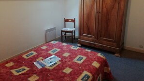 Een slaapkamer met een bed, een houten garderobe, een radiator en een dakraam.