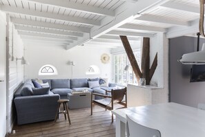 Un salon moderne avec un canapé bleu, une table basse en bois et un coin repas doté d’une table blanche.